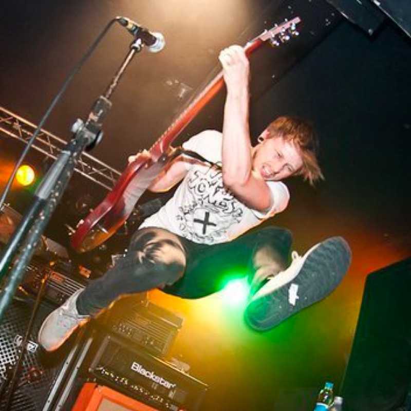 Ross jumping with a guitar at a show